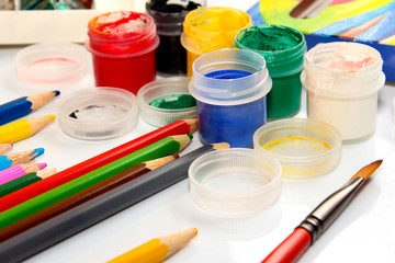Paints and pencils on white background