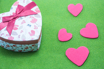 Hearth gift box and a little heart on green background