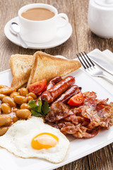 Full english breakfast with bacon, sausage, fried egg, baked bea
