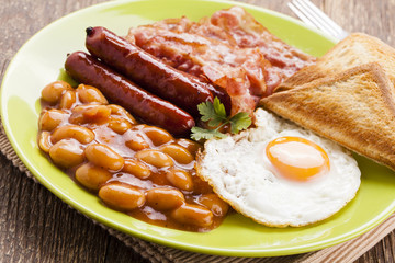 Full english breakfast with bacon, sausage, fried egg, baked bea