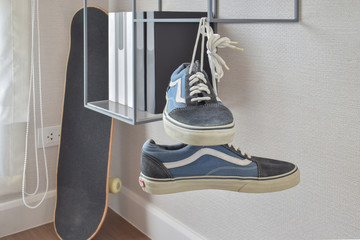 pair of casual blue sneaker shoes hanging on book shelve at home
