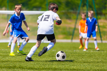 Young Boys Playing Soccer Football Match. Children Kicking Soccer Ball on a Sports Field. Youth football game and green Soccer Pitch in the Background.