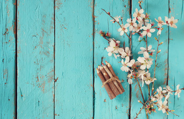image of spring white cherry blossoms tree next to wooden colorful pencils on blue wooden table. vintage filtered image
