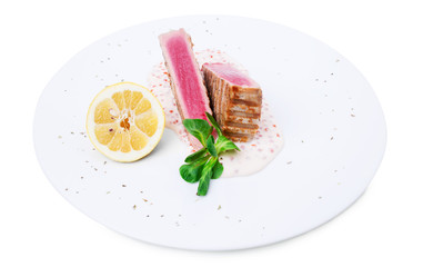 Grilled tuna fillet with sauce and lemon.