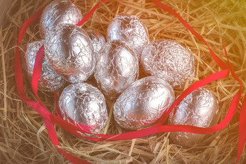 A group of chocolate eggs in a basket filled with hay