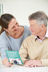 Senior Man With Adult Daughter Looking At Brochure For Retiremen