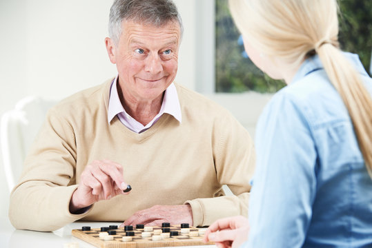 Senior Man Playing Checkers With Teenage Daughter