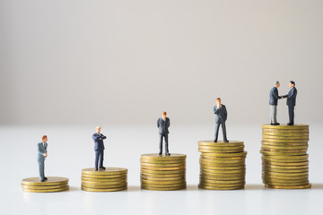Businessmen standing on coins stack.