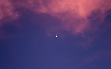 Blue sky and red clouds with moon in the center