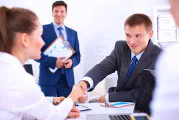 Business people shaking hands, finishing up a meeting, in office