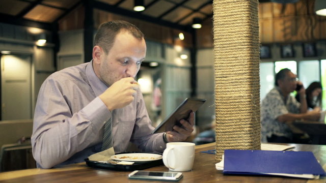 Young businessman with tablet eating and drinking in cafe HD
