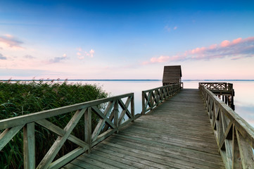 Obraz premium Wooden pier on calm lake at sunset