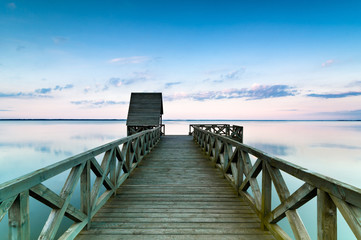 Fototapeta premium Wooden pier on calm lake at sunset