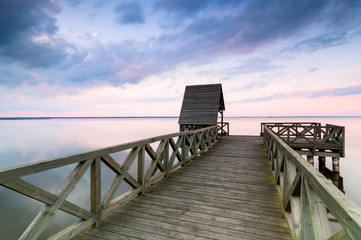 Wooden pier on calm lake at sunset