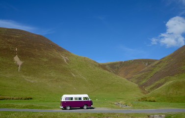 Purple camper van in the hills of Scotland