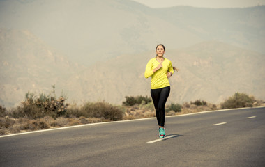 young attractive sport woman running on desert mountain asphalt road