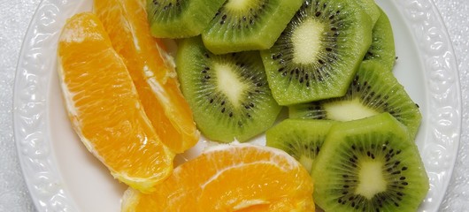 slices of kiwi and orange on a white plate