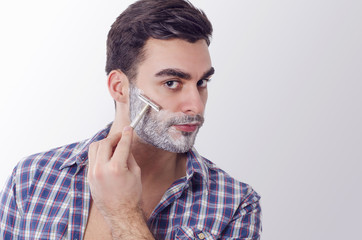 Closeup of handsome macho guy shaving with metal razor