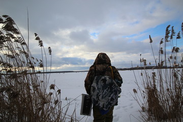 Мужчина в камуфляже  идет на зимнюю рыбалку на озеро © demon15