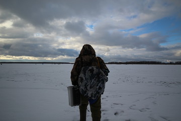 Мужчина-рыболов идет по льду ловить рыбу © demon15