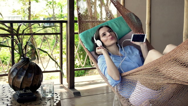 Beautiful woman listen music on hammock in the terrace
