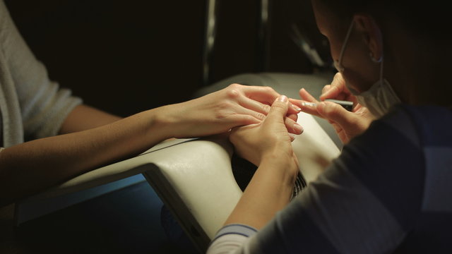 Woman in a nail salon receiving manicure by a beautician. Beauty treatment concept.