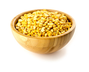 Bright yellow dried chickpea lentils in bamboo bowl