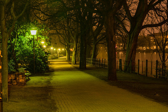 park near river Spree in Berlin at night, light up by street light