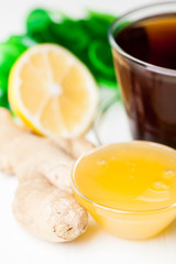 Cup of ginger tea with honey and lemon on white table