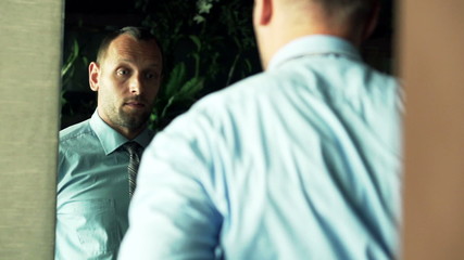 Businessman dressing up suit jacket in front of the mirror
