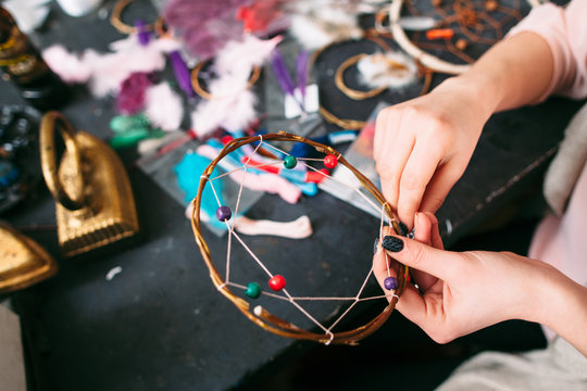 woman makes Dreamcatcher of sewing accessories.