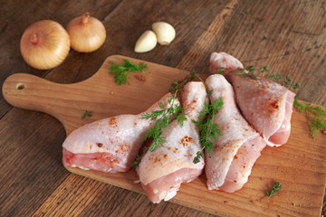 Raw chicken legs on wooden board.