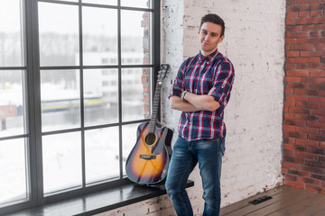 Fototapeta na wymiar Handsome casual style man with guitar smiling and looking at camera.