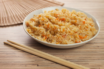 bowl of tasty cooked rice with chopsticks and fan