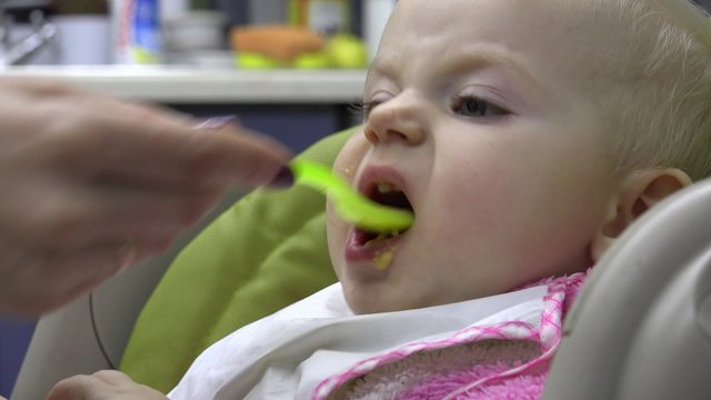Little Baby Feeding with Spoon. Closeup. 4K UltraHD video.