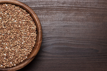 brown wooden bowl full of buckwheat background