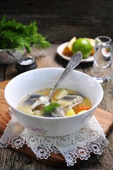 Sterlet fish soup with vegetables on wooden background.