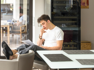 Junger Mann , etwa 20 Jahre, sitzt am Esstisch und liest