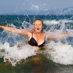 Young woman enjoying a dip in the sea on a background of foam and spray. Girl and sea wave. Bright sunny day. Selective focus.