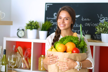 Young woman holding grocery shopping bag with vegetables 