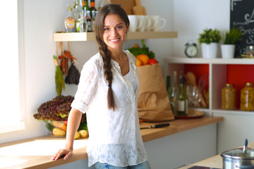 Young woman standing near desk in the kitchen