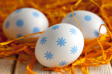 White and blue Easter eggs in orange nest