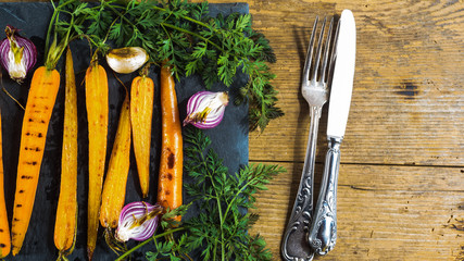 Grilled juicy carrots with parsley and vintage cutlery