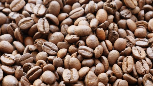 Arabica type coffee beans roasted and ready to be grinded slow tilting shallow DOF 4K 2160p UltraHD footage - Background made of coffee beans slow tilt
