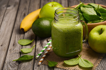 Green smoothie with apple, banana, avocado and spinach on a wooden rustic background. Horizontal permission. Selective focus. Copy space.