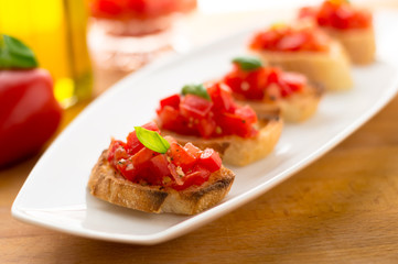 Italian tomato bruschetta served as appetizer, made with fresh ingredients like tomatoes, garlic, basil, bread and olive oil.