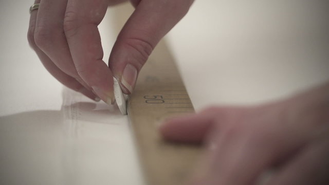 white woman works seamstress makes notch with soap on white fabrics in slow motion. macro