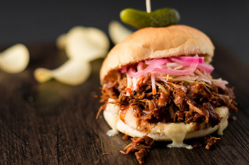 Slow cooked pulled pork with BBQ sauce, pickled onions, coleslaw and cheese served in a hamburger bun with dill pickle and chips as sides. It's a messy sandwich but so delicious!