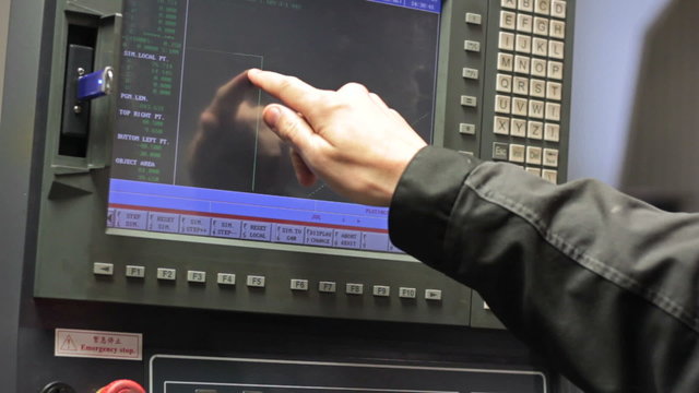Operator working with control panel of CNC machining centerchanging numbers
