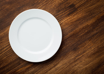 Empty white plate on wooden table